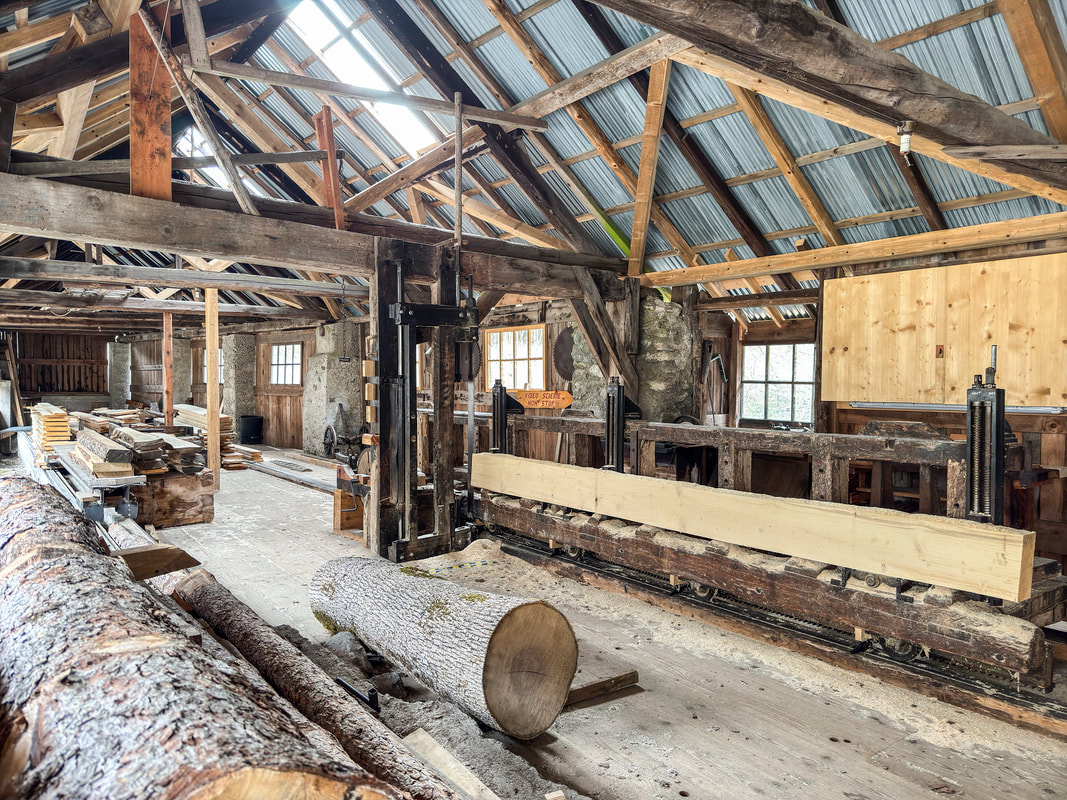 La scie battante et sa charpente de bois à l'intérieur de la scierie