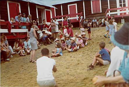 Enfants rassemblés dans la cour de la colonie, devant les chalets rouges